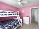 Bright bedroom with pink walls, a bunk bed, dresser, ceiling fan, and doorway view at 224 Market Hall St, Moncks Corner, SC 29461