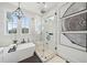 A bathroom showcasing a glass enclosed shower and soaking tub beneath bright windows with marble walls at 2621 Anchor Watch Dr, Wadmalaw Island, SC 29487