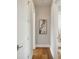 Hallway with hardwood floors, white doors and trim, and modern art hung in the center at 2621 Anchor Watch Dr, Wadmalaw Island, SC 29487