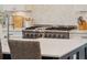 Close-up of kitchen island featuring a stainless steel gas range, marble countertops and white herringbone tile backsplash at 2621 Anchor Watch Dr, Wadmalaw Island, SC 29487