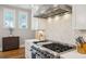 Well-lit kitchen features a stainless gas range with herringbone tile backsplash, white cabinets, and hardwood floors at 2621 Anchor Watch Dr, Wadmalaw Island, SC 29487