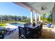 Covered patio with a black dining table, ceiling fan and view of the sparkling swimming pool and outdoor trees at 2621 Anchor Watch Dr, Wadmalaw Island, SC 29487