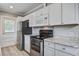 Kitchen featuring granite countertops, stainless appliances, white cabinets and light wood flooring at 2702 Decatur St, North Charleston, SC 29405