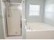 Bathroom features a glass enclosed shower, drop-in tub under a window with privacy blinds, and green paint at 9229 N Moreto Cir, Summerville, SC 29485