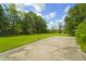 Large backyard featuring lush green grass, mature trees, and a concrete patio area at 1193 River Rd, Johns Island, SC 29455