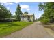 Classic home featuring a lush green lawn, complemented by a gravel driveway and mature trees at 1193 River Rd, Johns Island, SC 29455