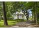 Charming home with classic architectural details, mature trees, and a welcoming fence-lined gravel driveway at 1193 River Rd, Johns Island, SC 29455