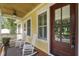 Cozy porch with a ceiling fan, rocking chairs, a door with sidelights, and decorative plants at 1193 River Rd, Johns Island, SC 29455