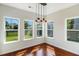 Dining area illuminated with a modern light fixture, showcasing hardwood floors and large windows at 1484 Milldam Pass, Johns Island, SC 29455