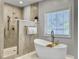 Bright bathroom featuring a modern standalone tub and a walk-in shower with sleek fixtures and tiled walls at 1491 Greenshade Way, Mount Pleasant, SC 29464