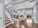 Open living room with hardwood floors, white staircase, fireplace, and plenty of natural light from large windows at 1523 Nautical Chart Dr, Charleston, SC 29414