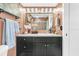Bathroom with a black vanity, marble countertops, vintage mirror and lighting, and decorative towels and accessories at 250 Little Oak Island Dr, Folly Beach, SC 29439
