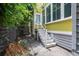 View of the backyard featuring green shrubs and trees, back entrance, and white stairs at 29 Hanover St, Charleston, SC 29403