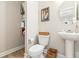 Bright powder room featuring pedestal sink, toilet with basket, and storage shelving on wood-look flooring at 3010 Grinnell St, Johns Island, SC 29455
