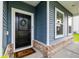 Inviting entryway featuring black door, decorative wreath, brick accents, and 'M' monogrammed welcome mat at 3010 Grinnell St, Johns Island, SC 29455