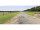 Gravel driveway leading to a horse stable with paddocks and green pastures on both sides at 3998 Capensis Ln, Ravenel, SC 29470