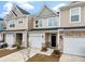 Street view of tan townhomes with one-car garages, black front doors, and manicured landscaping at 422 Duskywing Dr, Goose Creek, SC 29445