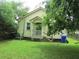 Home's backyard featuring a small porch and mature trees, plus an air conditioning unit and garbage cans at 47 Oswego St, Charleston, SC 29403