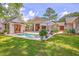 A tranquil backyard pool features stone surround, chairs, umbrella, and verdant green grass at 974 Cliffwood Dr, Mount Pleasant, SC 29464