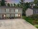 Two-story tan townhome with a long driveway, complemented by manicured landscaping and lush green trees at 1069 Lexi Ct, Ladson, SC 29456