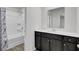 Modern bathroom featuring a tub with shower and dark wood vanity with a white countertop and large mirror at 110 Cardinal Flower Ct, Moncks Corner, SC 29461