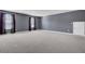 Large bonus room with neutral carpet, two windows with drapes, and a white door on a gray wall at 110 Cardinal Flower Ct, Moncks Corner, SC 29461