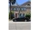 Charming brick townhouse featuring light blue shutters, decorative windows, and a neatly landscaped yard at 128 Queen St, Charleston, SC 29401