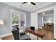 Light-filled home office featuring a wooden desk, ceiling fan, and views of the front yard at 1392 Founders Way, Mount Pleasant, SC 29464