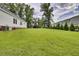 Wide backyard providing ample green space, enclosed by lush trees and houses with a backdrop of cloudy skies at 154 Patrick Ln, Summerville, SC 29483