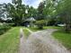 Front yard view of a gravel driveway leading to the home with a charming front porch at 1640 Dogwood Rd, Charleston, SC 29414