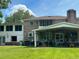 View of the backyard with a large green lawn, brick house, covered patio, and lush landscaping at 1866 Capri Dr, Charleston, SC 29407
