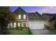 Charming two-story home featuring a manicured lawn, two-car garage, and inviting front porch at dusk at 2017 Asher Loop, Summerville, SC 29485