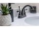 Close-up of modern vanity with decor, black faucet, white countertop, and decorative potted plant at 2172 Palermo Pl, North Charleston, SC 29406