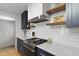 Modern kitchen featuring navy cabinets, stainless steel appliances, and floating wooden shelves at 2605 Mona Ave, Charleston, SC 29414