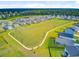 Charming aerial view of homes surrounding a park with soccer field, sidewalk and wooded area at 266 Torslanda Ln, Summerville, SC 29486