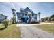 Charming elevated beach house with blue siding, double staircases, and lush palm trees at 3004 Point St, Edisto Island, SC 29438