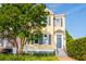 Lovely two-story yellow home with black shutters, blue door, and landscaped yard with mature tree at 49 Ashley Ave, Charleston, SC 29401