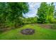 Spacious backyard featuring a fire pit, lush green grass, and mature trees in a serene setting at 5023 Manor Rd, Hollywood, SC 29449