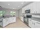 Well-lit kitchen featuring granite countertops, white cabinetry and black appliances at 5023 Manor Rd, Hollywood, SC 29449