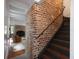 Staircase featuring a dark handrail, exposed brick wall, and wood stairs at 55 E Bay St, Charleston, SC 29401