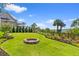Well-manicured backyard with a fire pit, mature landscaping, and views of the lake at 553 Old Compass Rd, Daniel Island, SC 29492
