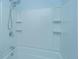 Close-up of a white tiled shower-over-tub with a shower head and molded shelves at 765 Certificate Ct, Charleston, SC 29414