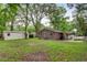 View of the backyard featuring a brick home, covered patio, storage building and mature trees at 10 Teaneck Rd, Goose Creek, SC 29445
