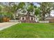 Charming brick home features a well-manicured lawn, mature trees, and a classic white picket fence at 10 Teaneck Rd, Goose Creek, SC 29445