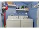 Cozy laundry room with washer, dryer, decorative shelving and a mounted vacuum cleaner on a cool blue wall at 10 Teaneck Rd, Goose Creek, SC 29445