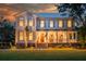 Stunning two-story home with a metal roof, large front porch and manicured lawn at sunset at 108 Live Oak Dr, Mount Pleasant, SC 29464