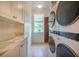 Charming laundry room with modern stacked washer/dryer, marble countertop sink, and patterned wallpaper at 108 Live Oak Dr, Mount Pleasant, SC 29464