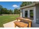 Outdoor patio with wooden furniture overlooking a spacious, fenced backyard and a view of surrounding trees at 108 Plume Poppy Ln, Ladson, SC 29456