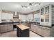 Charming kitchen boasts a brick accent wall, light gray cabinets, a stainless steel range hood, and a central island at 108 Plume Poppy Ln, Ladson, SC 29456