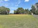Well-maintained baseball field with a backstop, open green space, and lush surrounding trees under a blue sky at 2142 Golfview Dr, Charleston, SC 29412